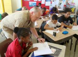 Author Steve Swinburne looks over Rex Cazaubon's opening paragraph while his classmates are lost in their writing.